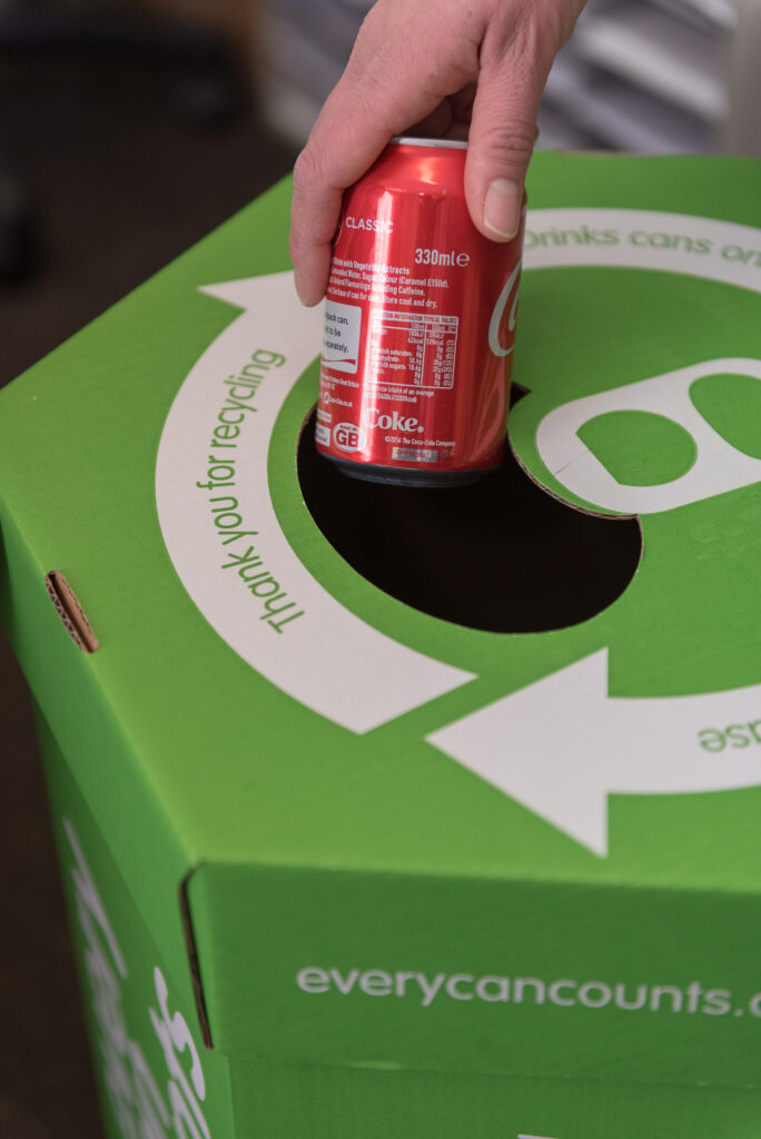 An empty drink can being recycled into an Every Can Counts Collection box. 